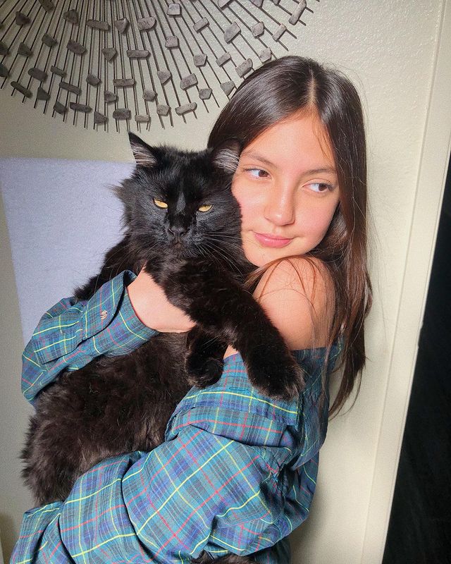 Elle Paris Legaspi in a blue check shirt holding her black cat.